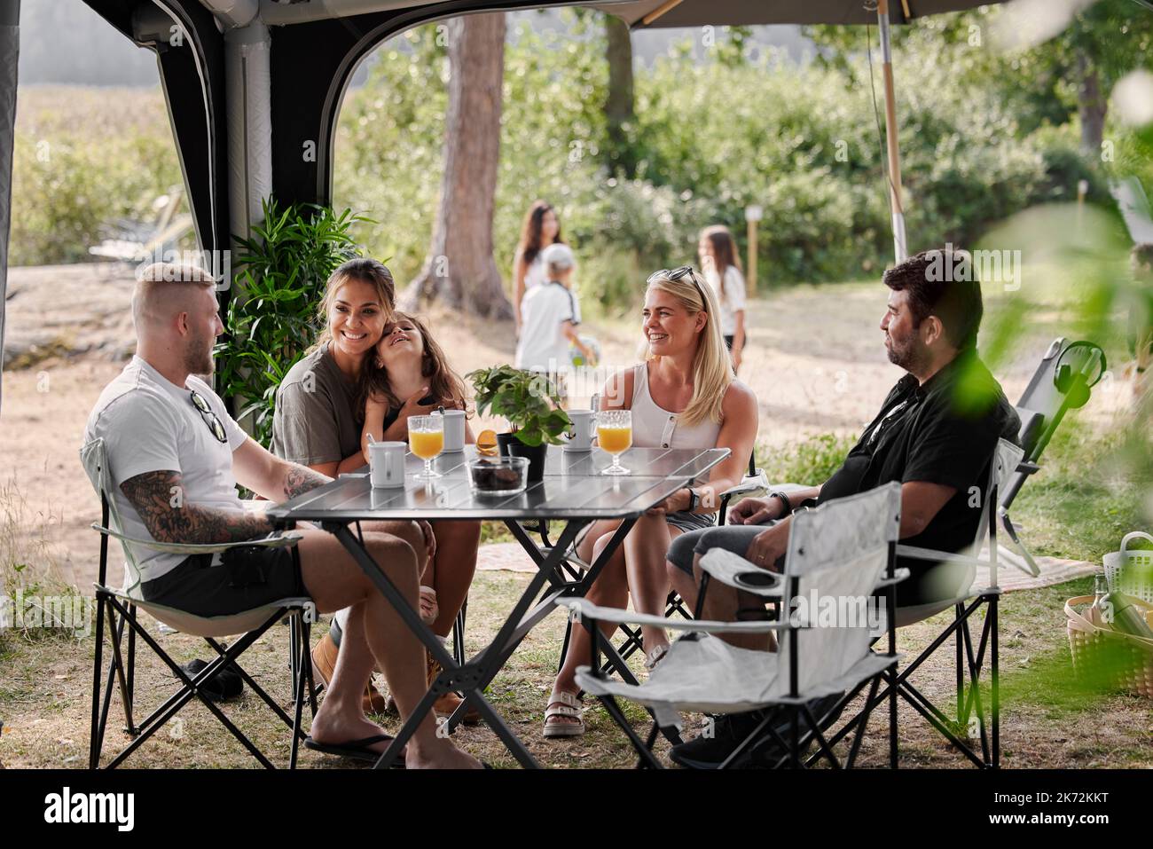 Amis avec des enfants se détendant sous le belvédère du jardin Banque D'Images