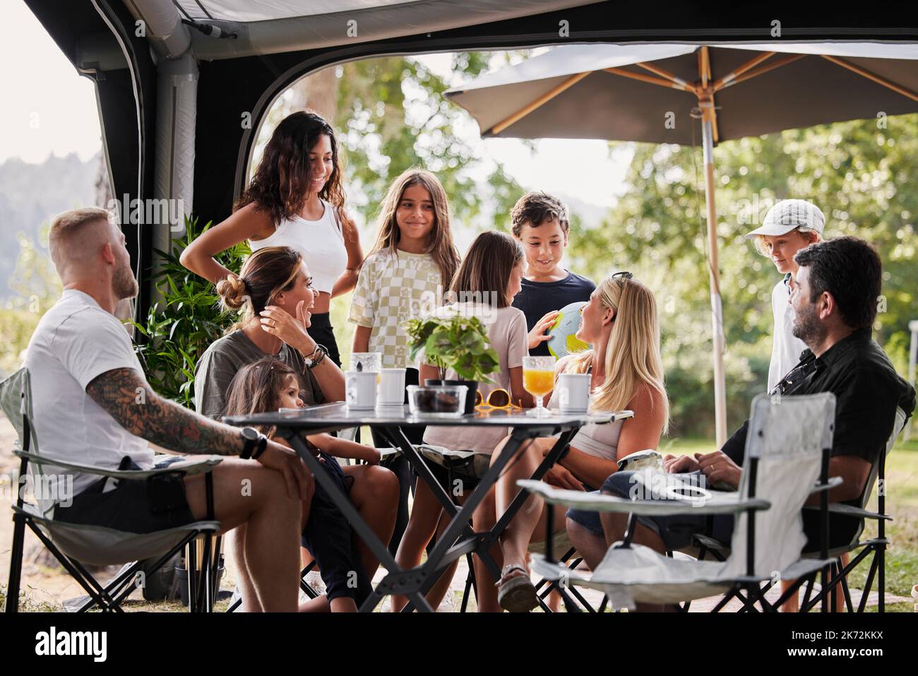 Amis avec des enfants se détendant sous le belvédère du jardin Banque D'Images