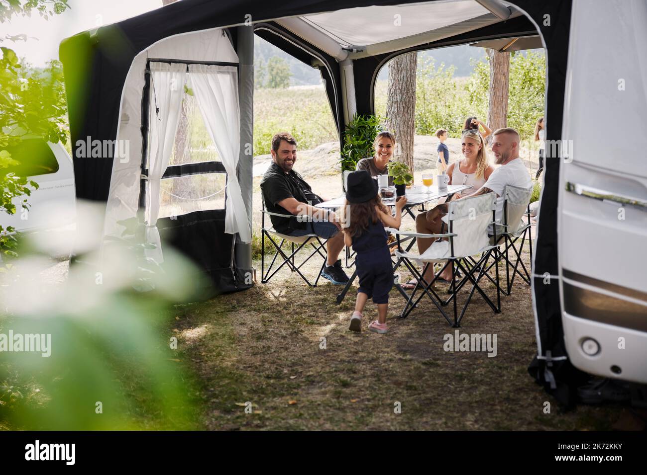 Amis avec des enfants se détendant sous le belvédère du jardin Banque D'Images