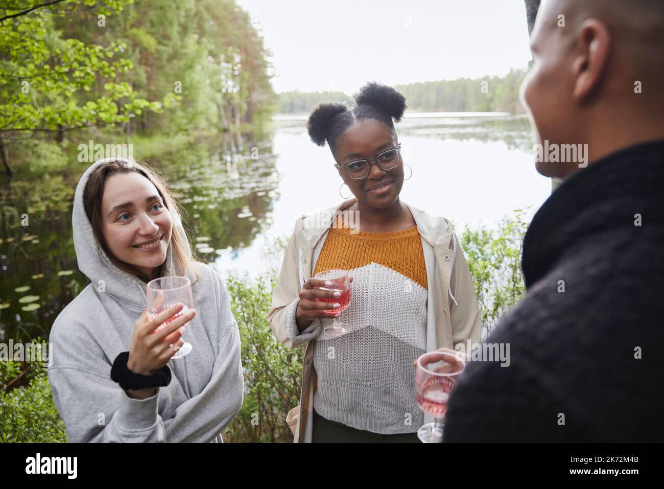 Amis qui boivent du vin au bord du lac Banque D'Images