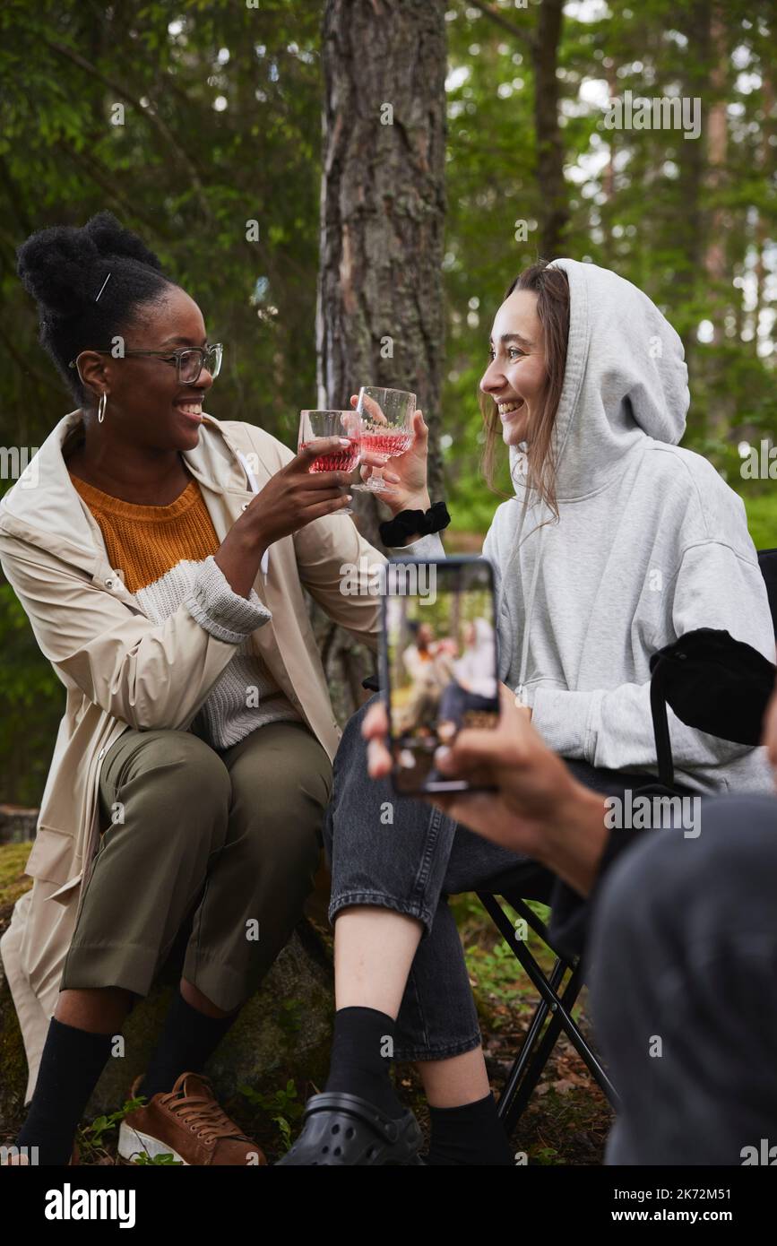 Des amis qui ont du pain grillé au camping en forêt Banque D'Images