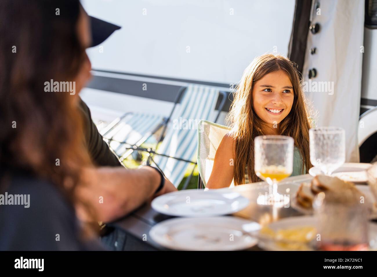 Smiling girl sitting at table Banque D'Images