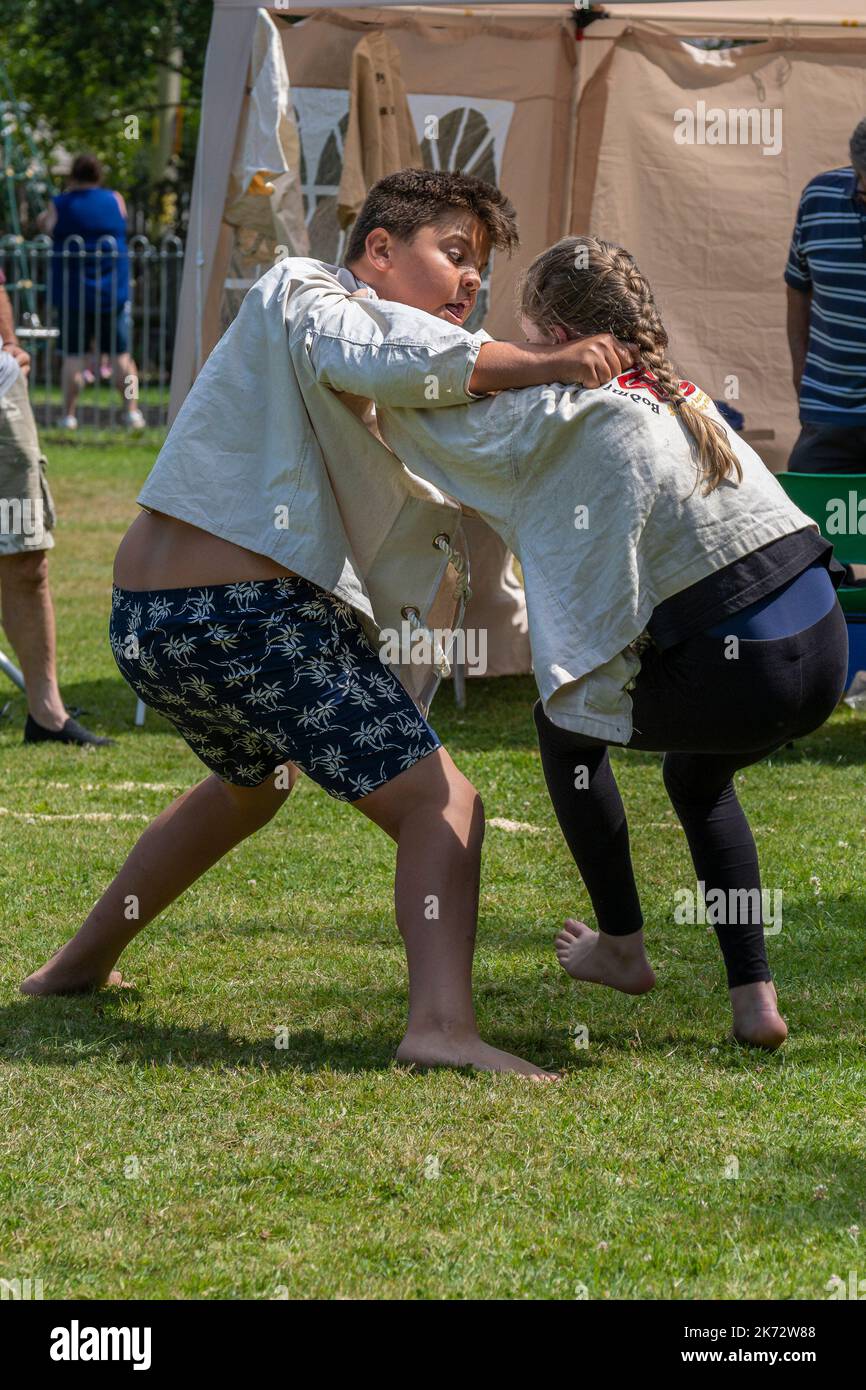 Une jeune fille en compétition avec un grand garçon dans le Grand Tournoi de Wrestling Cornish sur le pittoresque village vert de St Mawgan à Pydar à Cornwa Banque D'Images