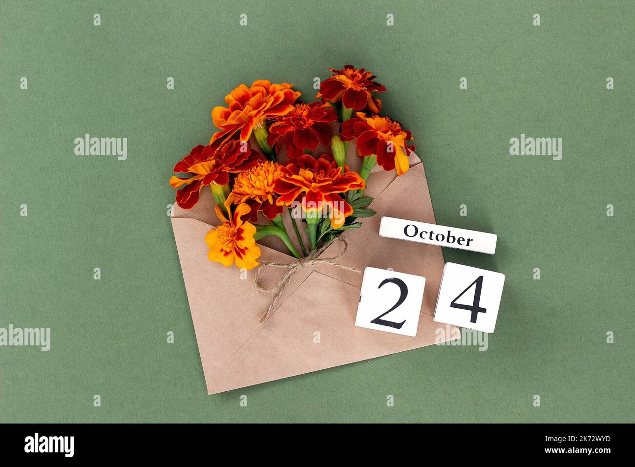24 octobre. Bouquet de fleurs orange en enveloppe artisanale et date calendrier sur fond vert. Concept minimal Hello Fall. Modèle pour votre conception, gr Banque D'Images