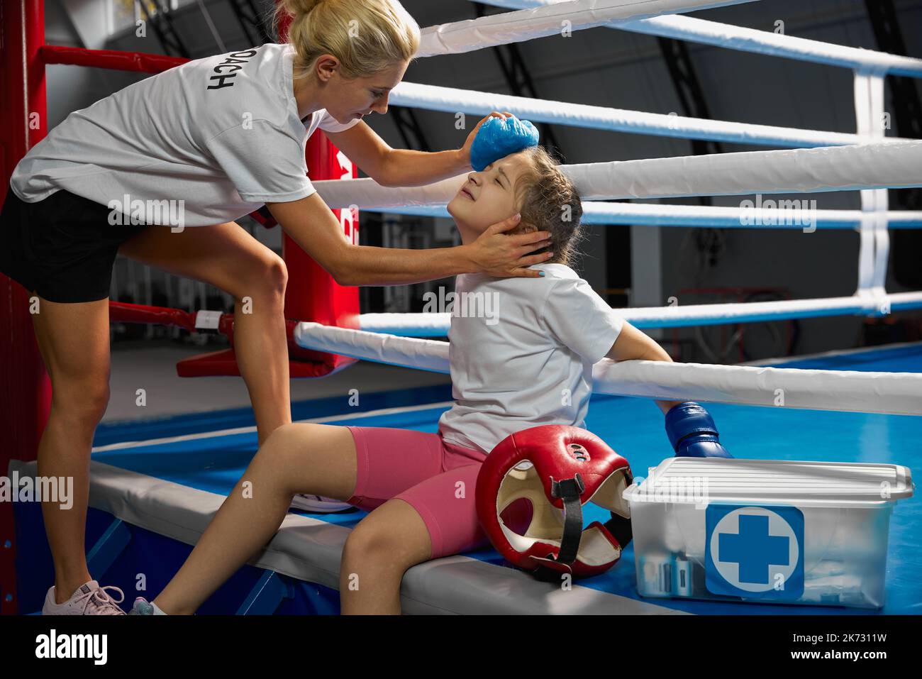 Entraîneur personnel, entraîneur d'équipe fournit les premiers soins à un athlète avec une blessure à la tête. Entraînement de boxe dans la salle de gym. Sport, médecine, étudier Banque D'Images