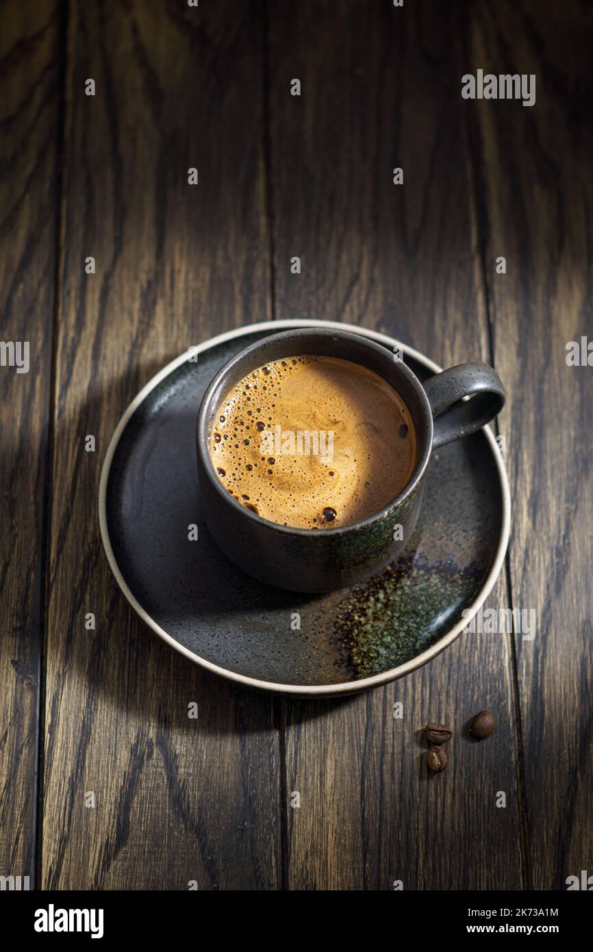 Tasse à café noir moussant sur fond de bois rustique Banque D'Images
