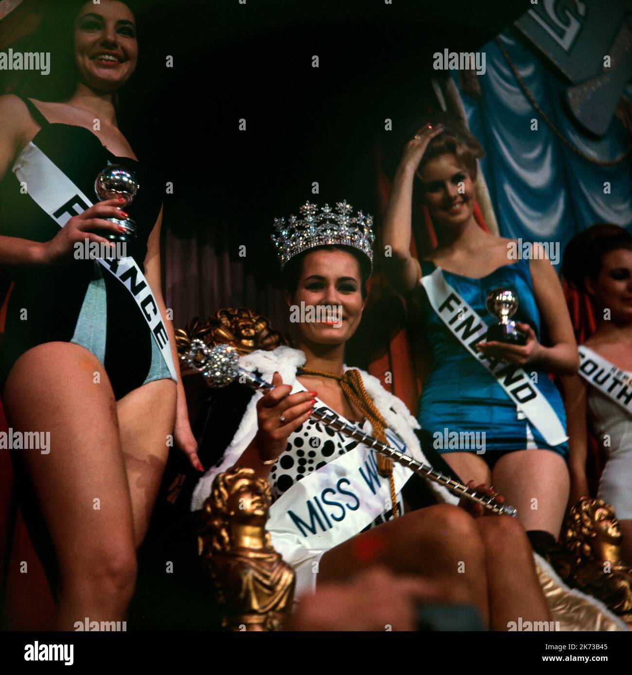 La gagnante du titre « monde du son » 1962, Catharina Lodders des pays-Bas, avec Miss France et Miss Finlande à ses côtés. Elle est assise sur le trône portant une couronne. Le concours a eu lieu à Londres. Banque D'Images