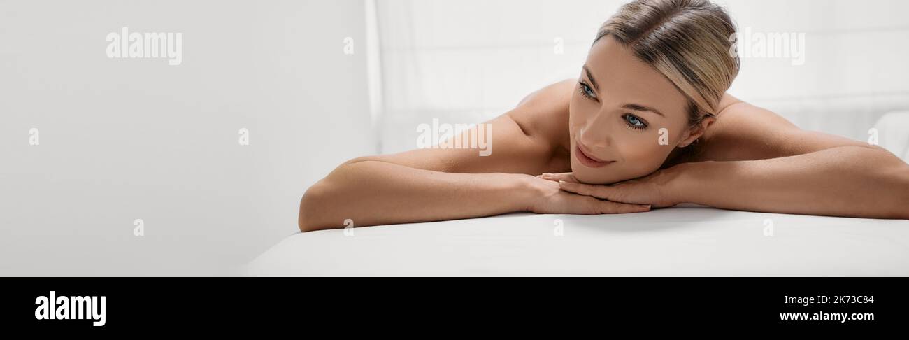 Spa pour femmes avec massage, concept. Une jolie femme aux yeux fermés se détend sur une table de massage après des soins spa Banque D'Images
