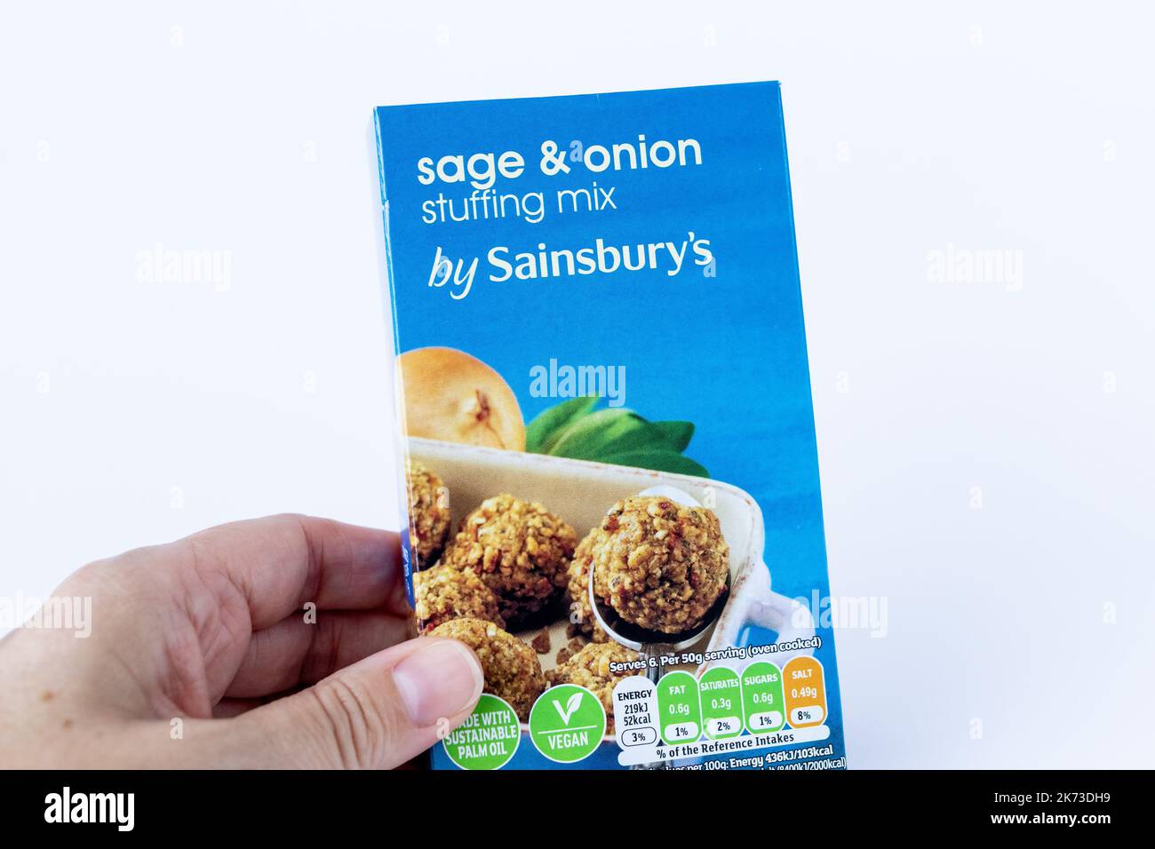 Main féminine tenant une boîte de mélange à la sauge et à l'oignon de la marque Sainsburys Banque D'Images