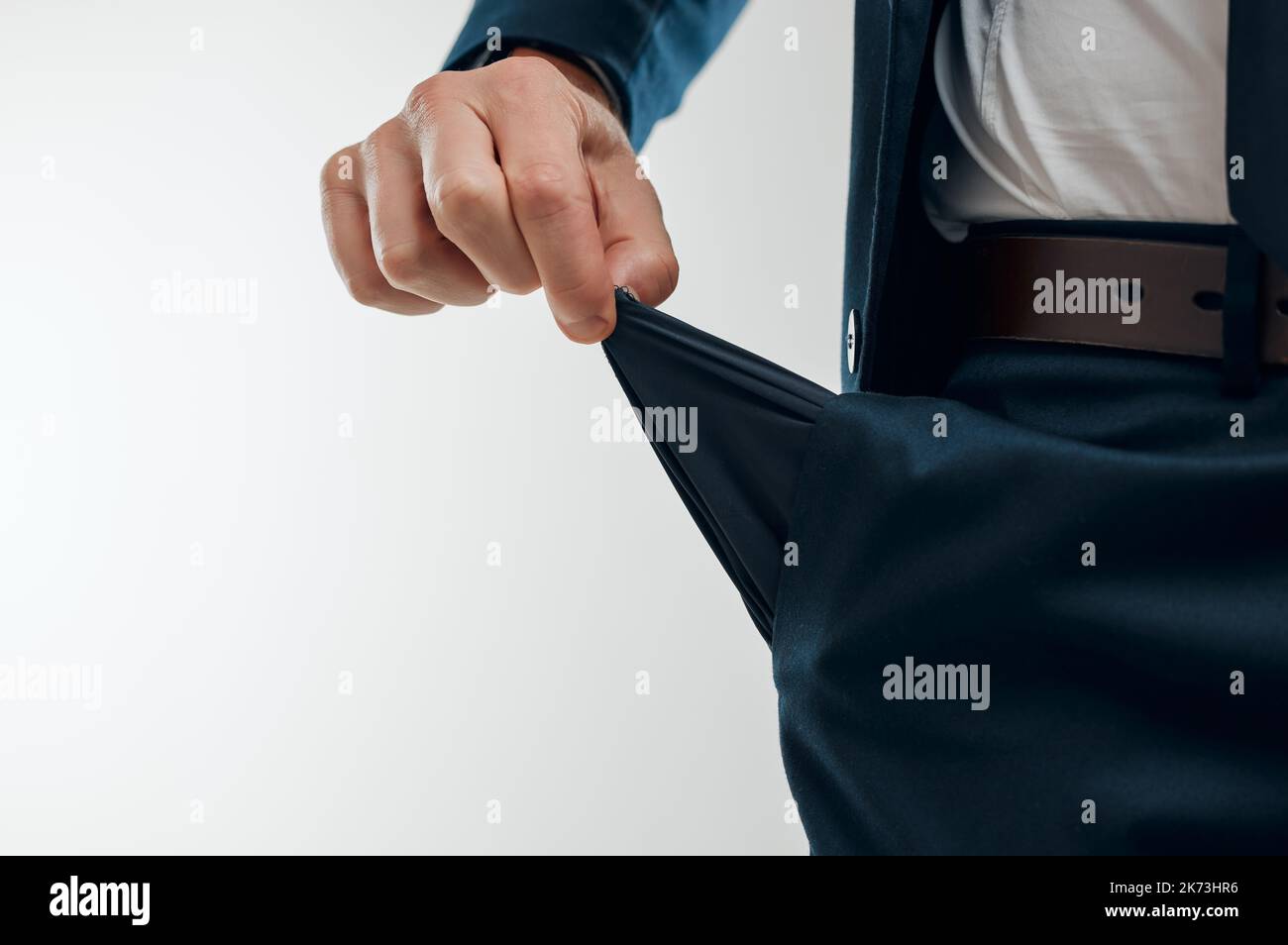 Complètement sans difficulté. Photo studio d'un homme d'affaires méconnu tirant une poche vide de son pantalon sur un fond blanc. Banque D'Images