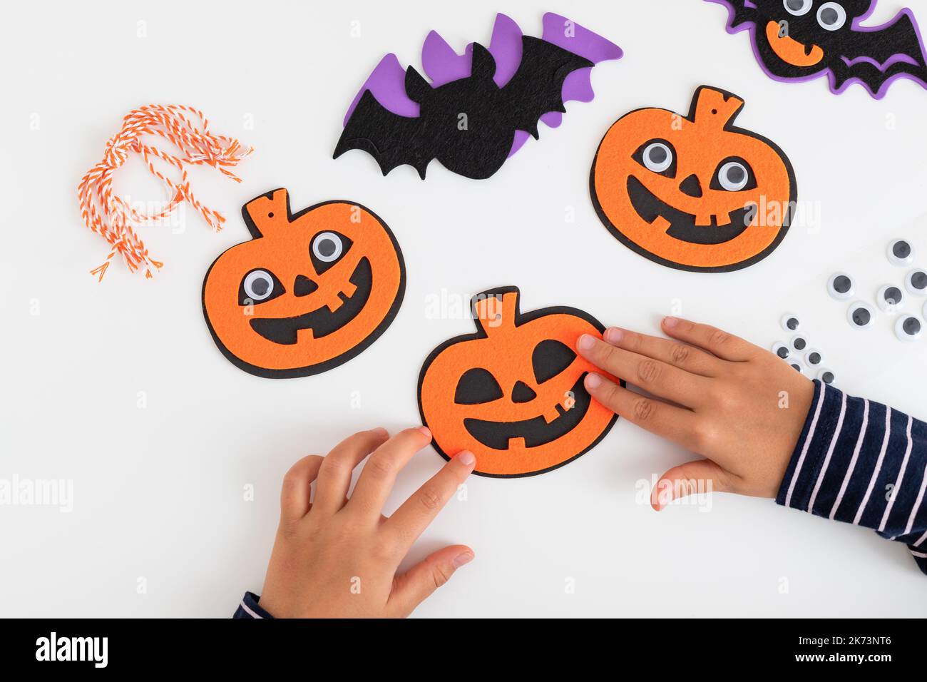enfants qui font des citrouilles en feutre et des chauves-souris assis à la table Banque D'Images