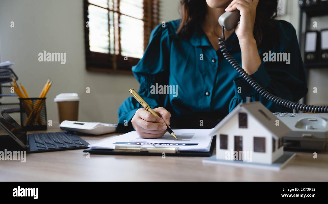 Contrat de prêt à domicile. modèle de maison sur le bureau de travail avec agent immobilier professionnel faisant appel d'affaires parlant au téléphone avec le client pour signer Banque D'Images