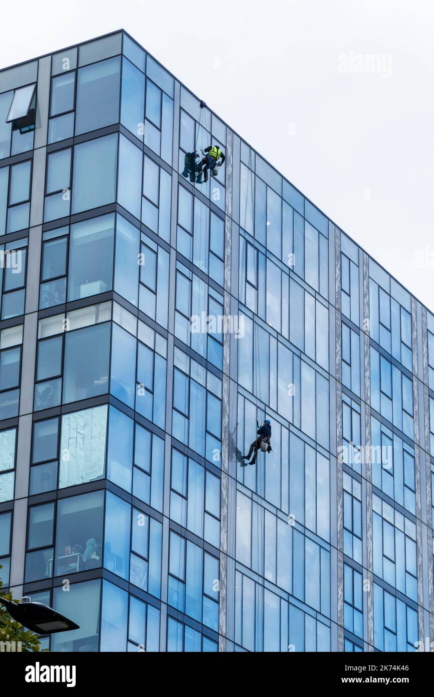 Deux hommes suspendus sur des cordes nettoyant les fenêtres d'une tour d'appartement, Londres, Royaume-Uni Banque D'Images