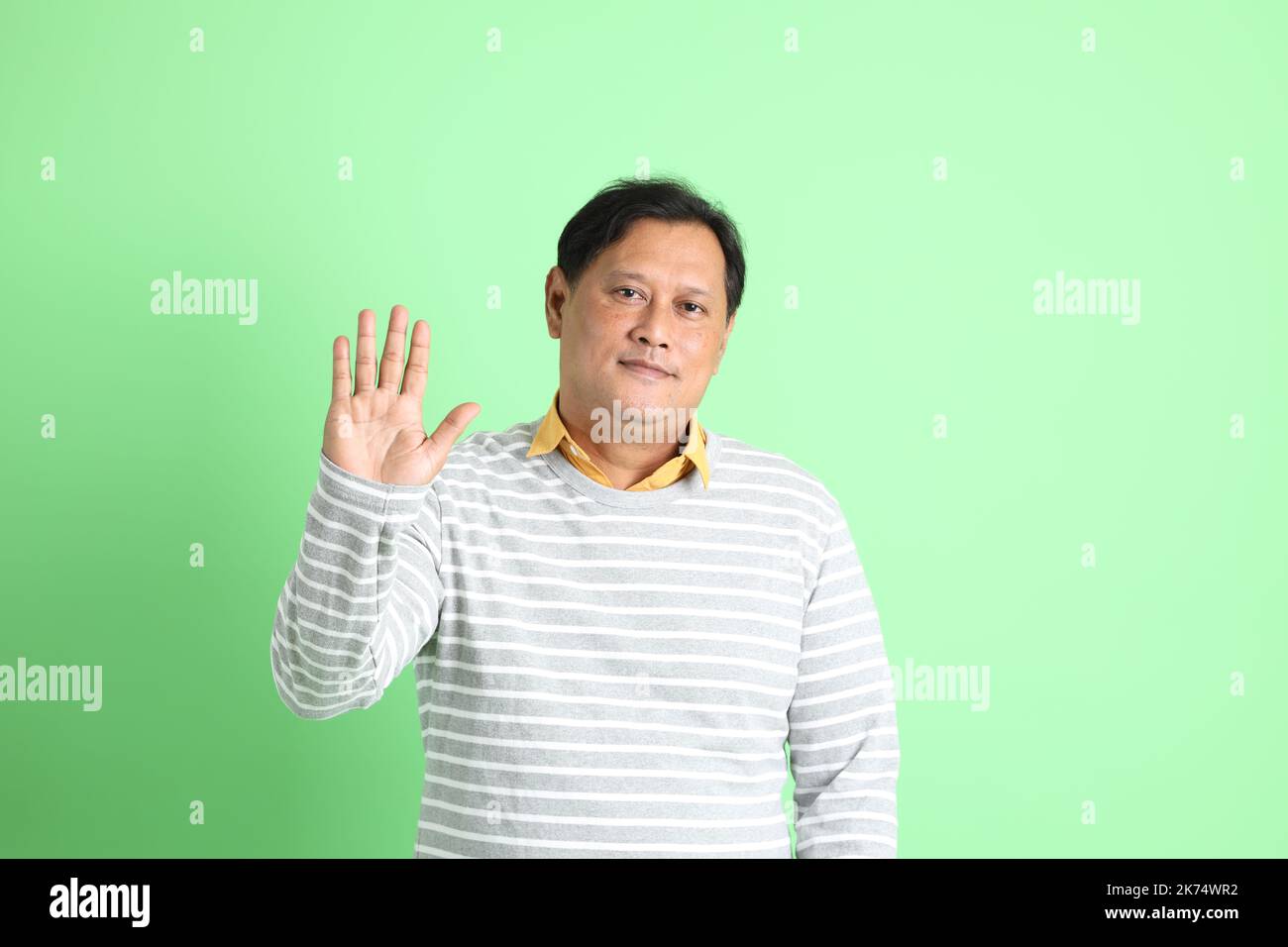 L'homme asiatique de 40s adultes en surpoids se tenant sur fond vert. Banque D'Images