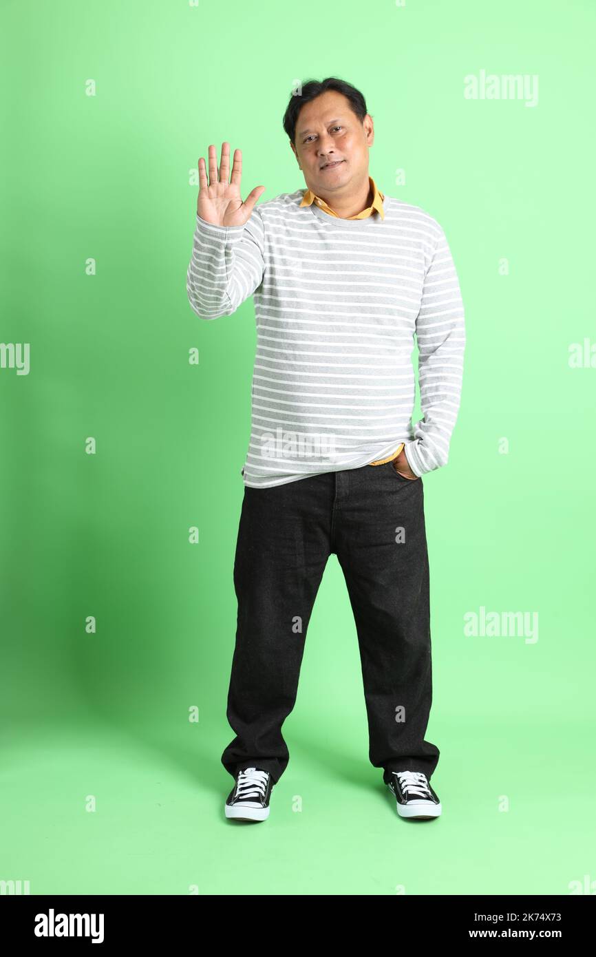 L'homme asiatique de 40s adultes en surpoids se tenant sur fond vert. Banque D'Images