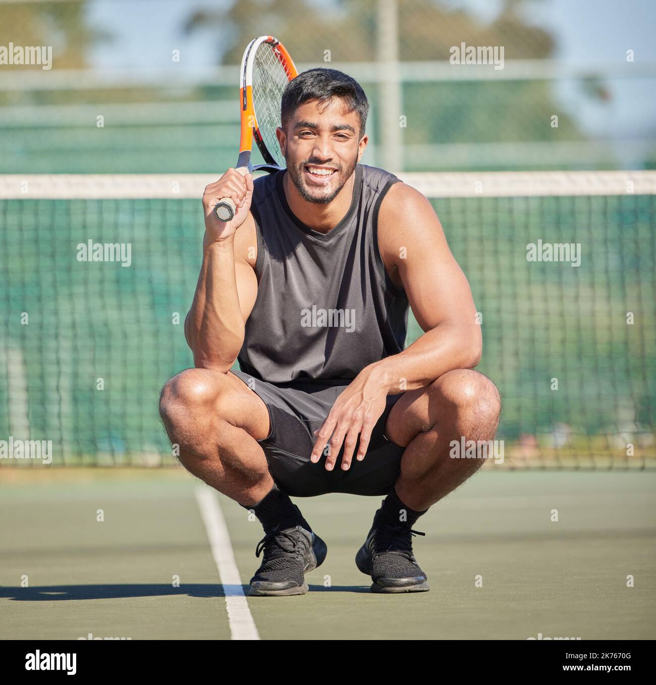 Je vous mets au défi d'une partie de tennis. Prise de vue en longueur d'un beau jeune homme qui s'est accroupi à l'extérieur pendant une partie de tennis. Banque D'Images