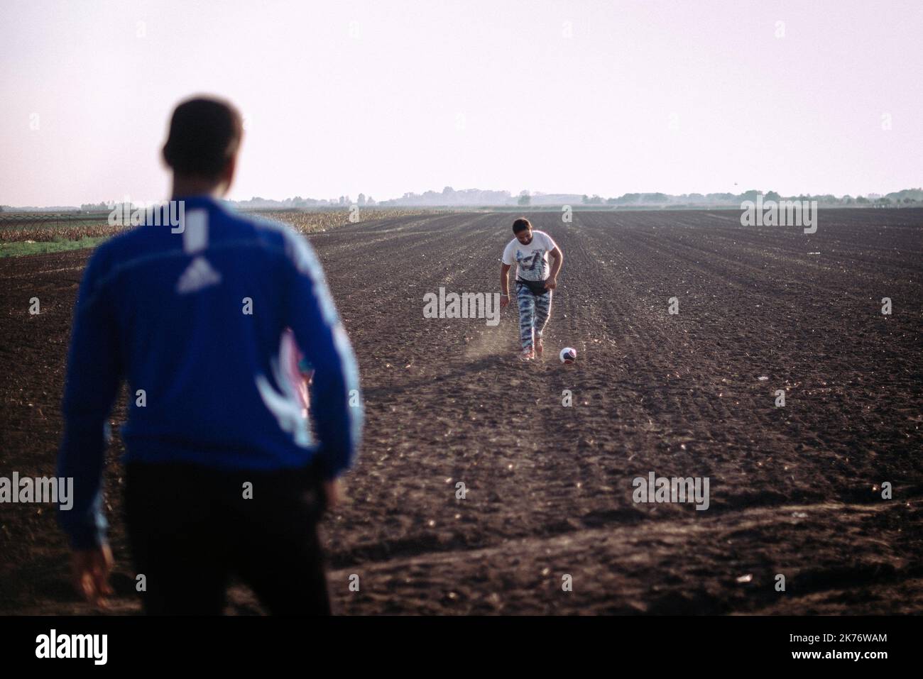 Les réfugiés qui attendent de monter à bord d'un bus pour le camp de Roszke attendent près de la frontière serbe-hongroise un match de football Banque D'Images