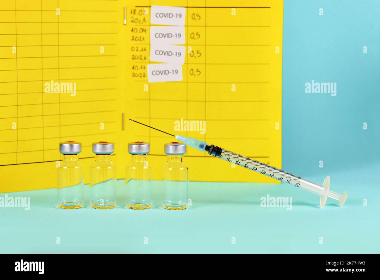 Vaccin de rappel Corona concept avec 4 flacons avec seringues et certificat de vaccination en arrière-plan avec espace de copie Banque D'Images