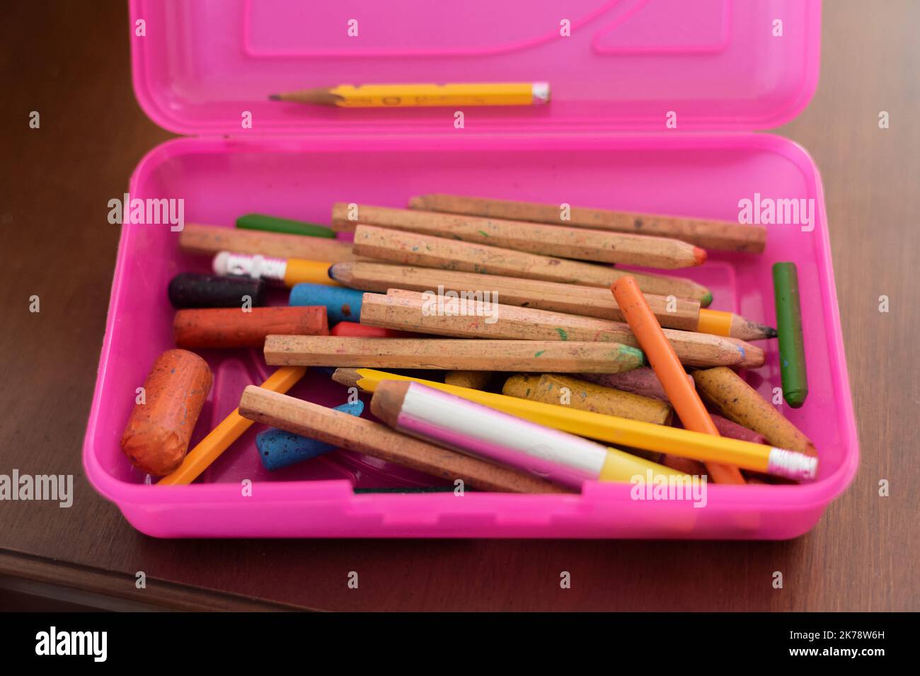 Divers crayons et crayons dans un coffret en plastique rose placé sur la table Banque D'Images