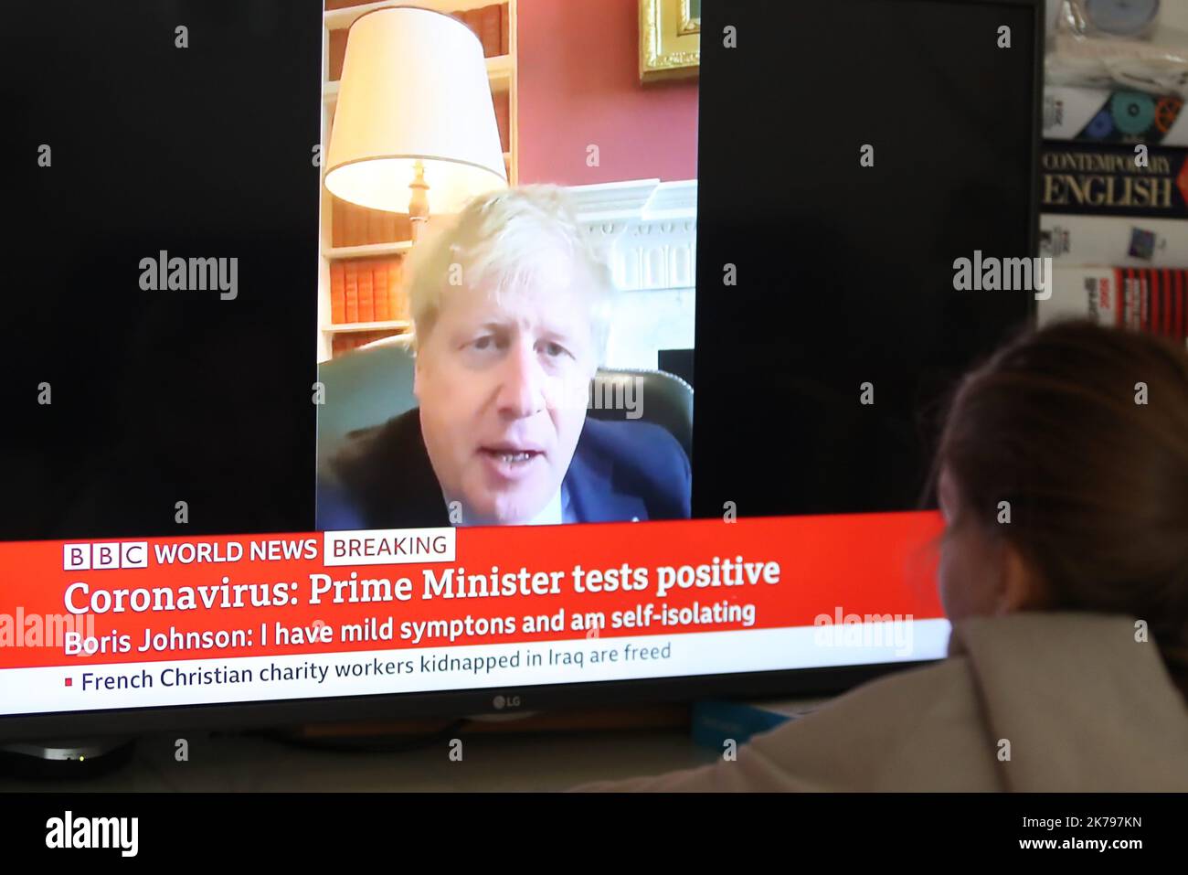 Une jeune fille regarde BBC World News comme une rupture de la presse que le Premier ministre britannique Boris Johnson a testé positif pour le coronavirus après avoir éprouvé des symptômes légers Banque D'Images