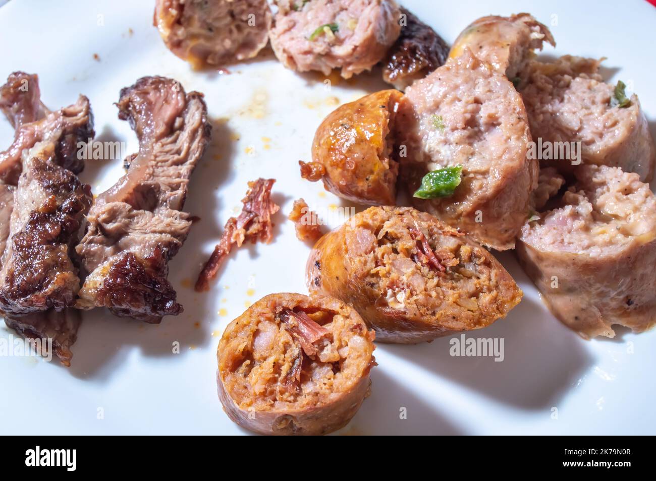 La saucisse rôtie et coupée en tranches sur un plat blanc avec de petits morceaux de viande à côté de la saveur de saucisse est pastrami. Banque D'Images