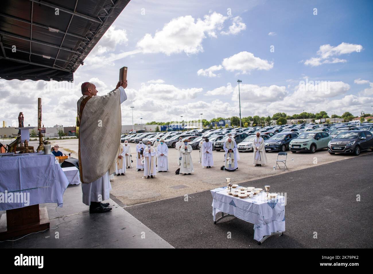 L'évêque français François Touvet (L) tient la Bible devant les adorateurs dans leurs voitures lors de la célébration de la deuxième messe du drive-in à Chalons-en-Champagne, dans le nord-est de la France, le 24 mai 2020. Les églises ont rouvert leurs portes au public après la levée des restrictions de confinement sur les lieux de culte. Banque D'Images