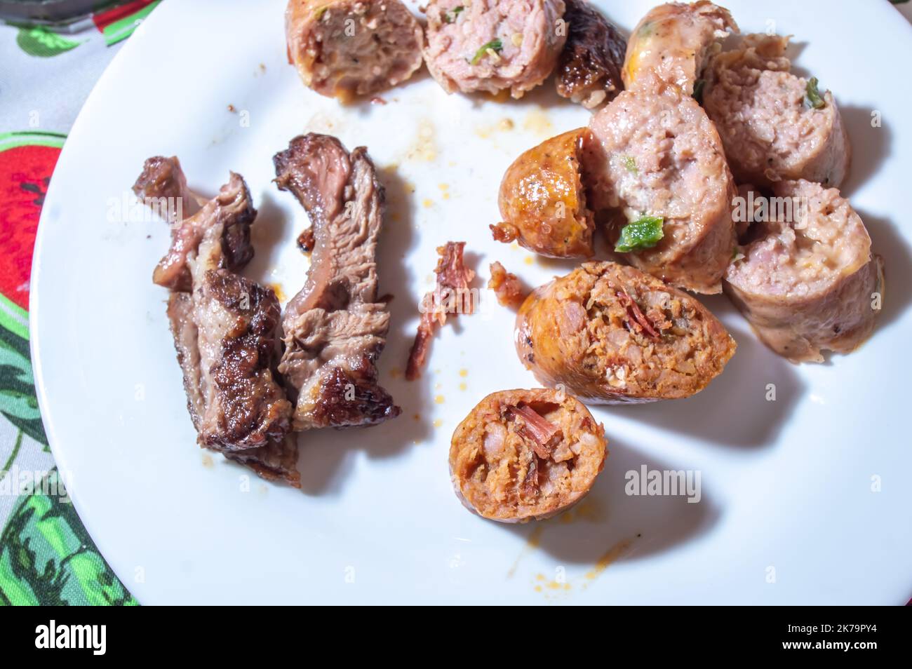 La saucisse rôtie et coupée en tranches sur un plat blanc avec de petits morceaux de viande à côté de la saveur de saucisse est pastrami. Banque D'Images