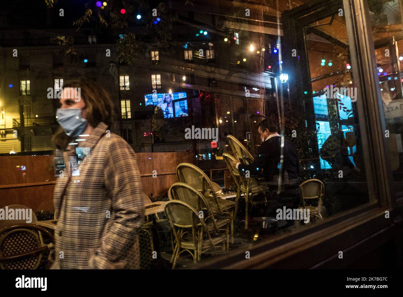 ©Michael Bunel / le Pictorium/MAXPPP - Michael Bunel / le Pictorium - 22/10/2020 - France / Ile-de-France / Paris - une femme masquee passe devant un serveur en train de ranger les chapes de la terrasse de son bar. le livre feu fait ses débuts dans 5 minutes et cours de 21 heures a 6 heures du matin. Paris est sous forme feu feu, de 21 heure a 6 heure du matin, depuis le debut de la semaine. Une mesure par le gouvernement pour éviter la propagation du virus, COVID 19. 22 octobre 2020. Paris, France. / 22/10/2020 - France / Ile-de-France (région) / Paris - Une femme masquée passe devant une attente Banque D'Images