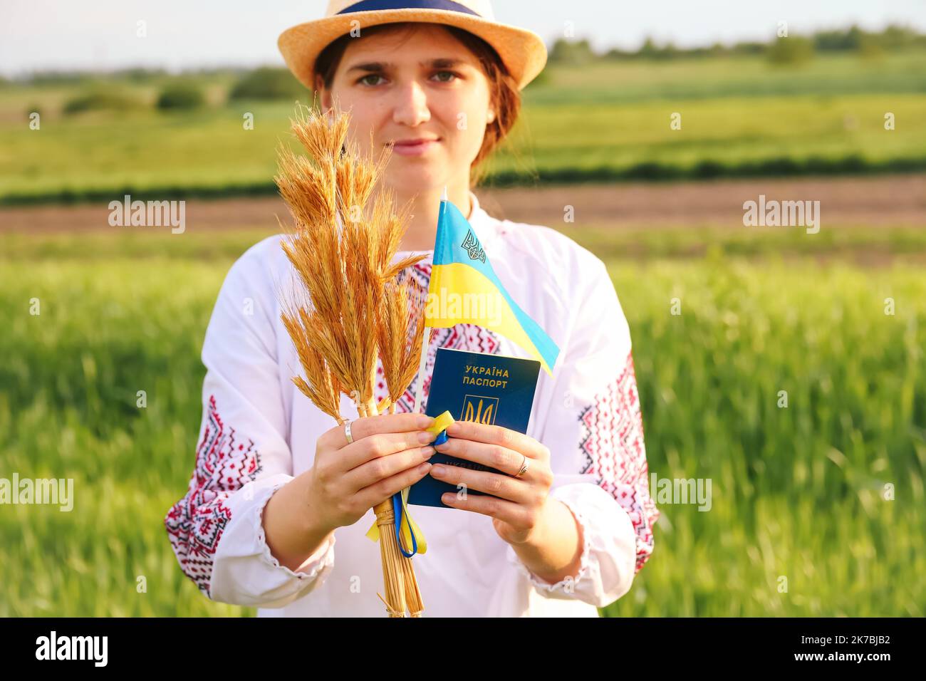 Recentrer le portrait de la jeune femme ukrainienne. Bouquet d'épillets dorés mûrs de blé attachés sur le fond de la nature du pré. Montrant le drapeau de l'Ukraine. Sourire Banque D'Images