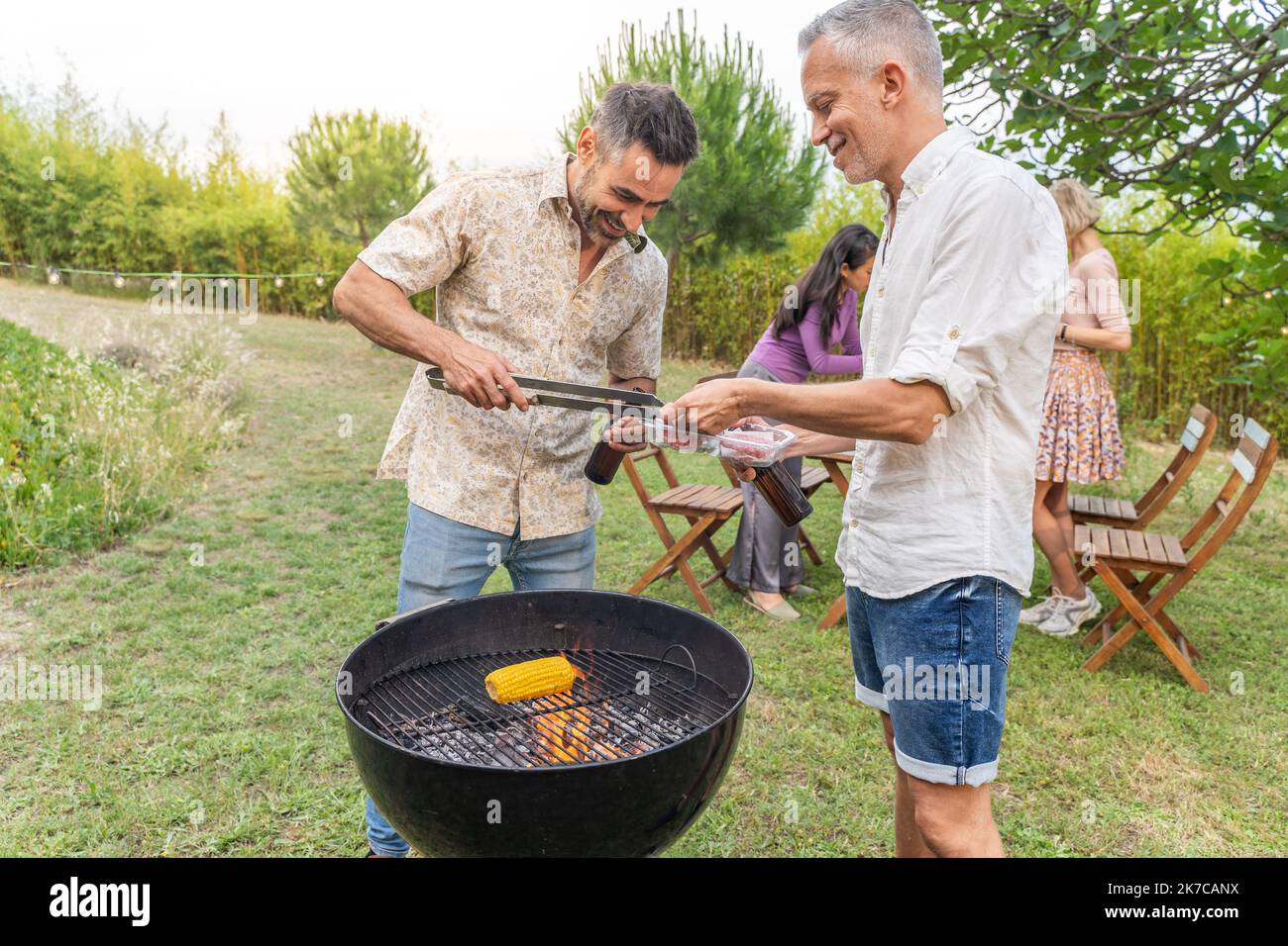 Des gens multiraciaux autour du barbecue souriant heureux et riant ensemble. Concept de joie. Banque D'Images