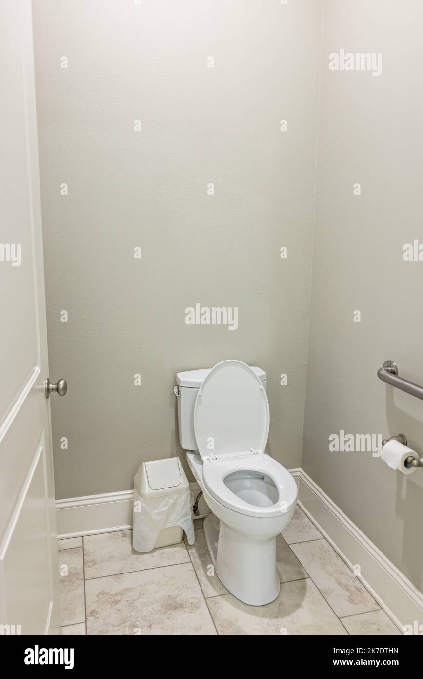 Une petite salle de bains avec des murs gris et des toilettes avec des sols carrelés dans une nouvelle maison de construction Banque D'Images