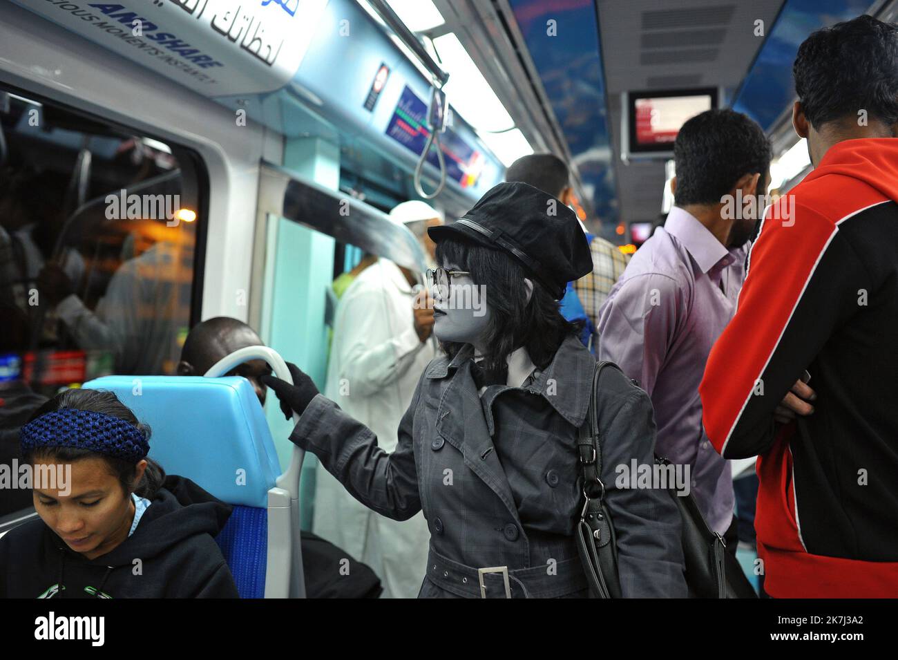 Une jeune femme amusante, un maquillage et un costume triptieux en niveaux de gris pour Halloween prend le métro à Dubaï, aux Émirats arabes Unis, contrairement à la réalité colorée. Banque D'Images