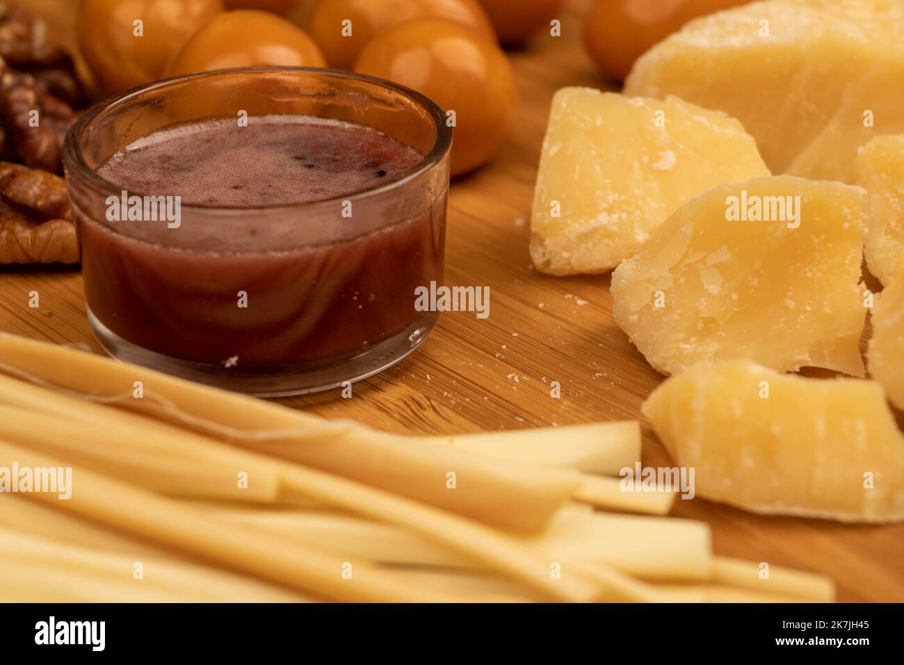 Diverses variétés de fromage, de noix, d'œufs de caille fumés et de miel dans un vase en verre sur une surface en bois. Banque D'Images