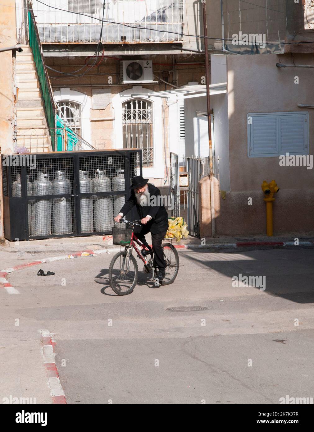 Un vieil homme juif orthodoxe à vélo dans le quartier de MEA He'arim à Jérusalem, en Israël. Banque D'Images