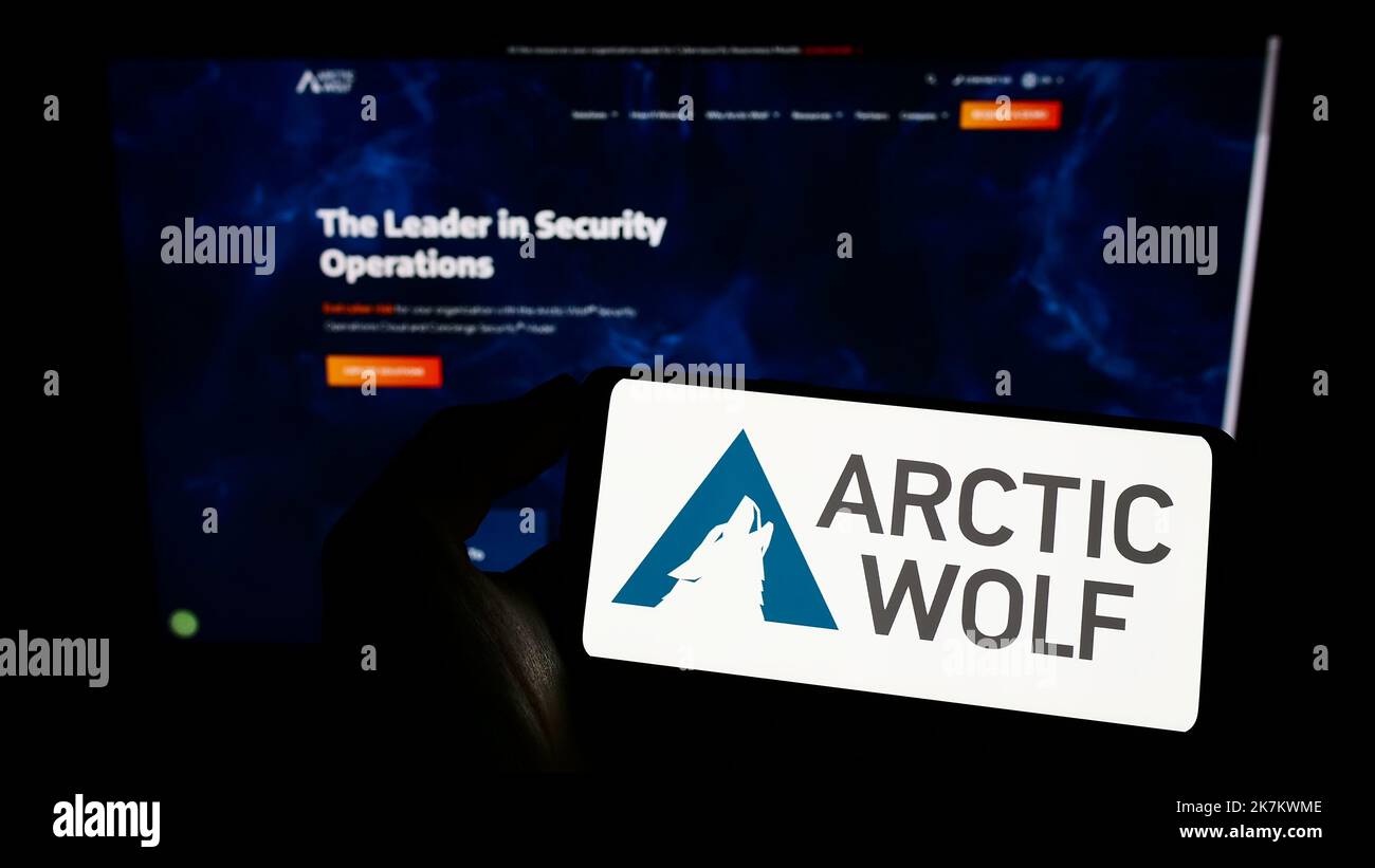 Personne tenant un téléphone portable portant le logo de la société de cybersécurité Arctic Wolf Networks Inc. À l'écran devant la page Web. Mise au point sur l'affichage du téléphone. Banque D'Images