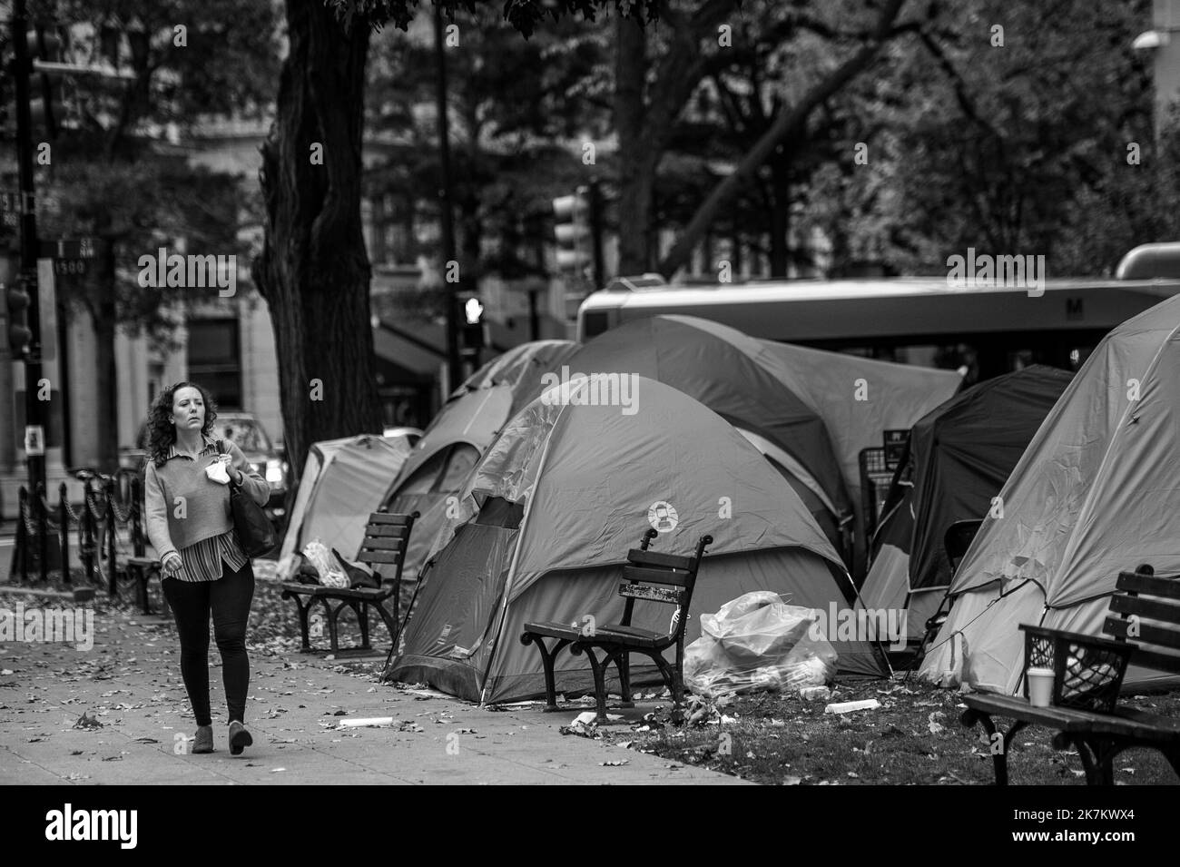 Pendant les heures de pointe du matin, les gens passent devant les sans-abri de la place McPherson à Washington, DC, lundi, 17 octobre 2022. Il y a environ trois douzaines de tentes dans le parc, avec une buanderie accrochée sur des branches d'arbres, des chaises, des tables et même deux salles de bains portatives. Il s'agit de l'une des nombreuses communautés sans abri, y compris les vétérans américains, dans la capitale de nations, dans des lieux de haute visibilité publique, coexistant avec les résidents locaux. Crédit : Rod Lamkey/CNP Banque D'Images