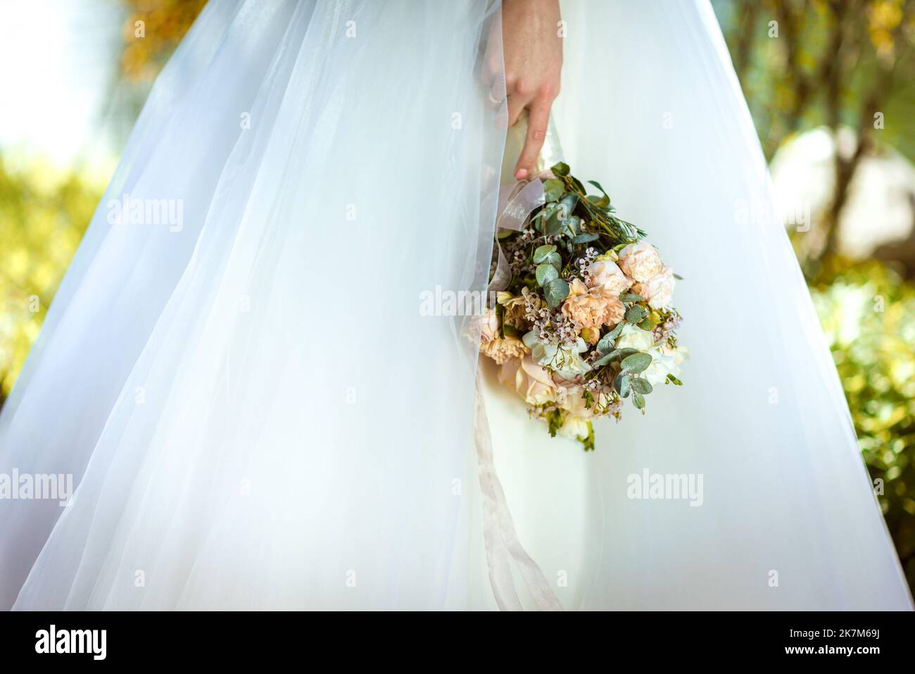 La mariée tient un bouquet de mariage de roses dans ses mains, des fleurs de jour de mariage. Beau bouquet de fleurs de mariage bohème. Fille dans une robe avec un bouq Banque D'Images