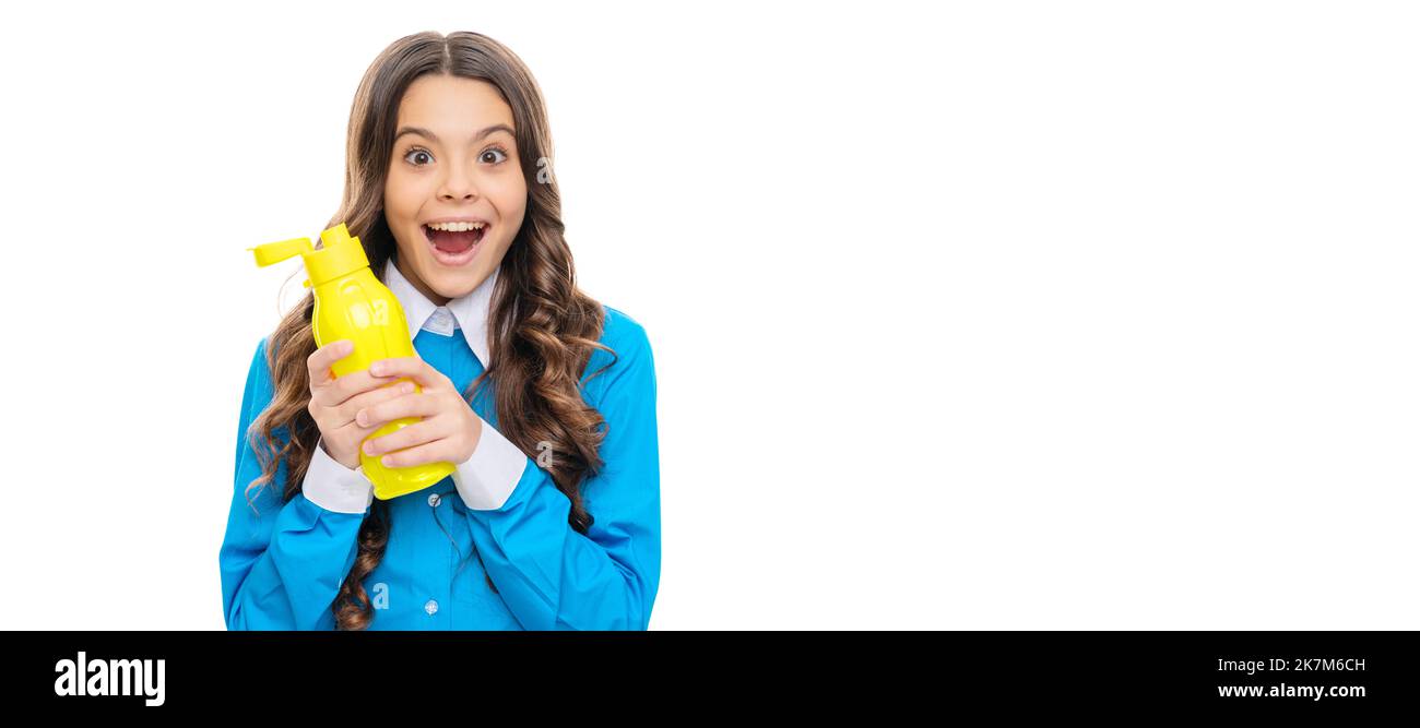 Un enfant heureux tient une bouteille en plastique jaune avec des produits laitiers isolés sur du yogourt blanc. Affiche horizontale de visage enfant isolé, en-tête de bannière, espace de copie. Banque D'Images