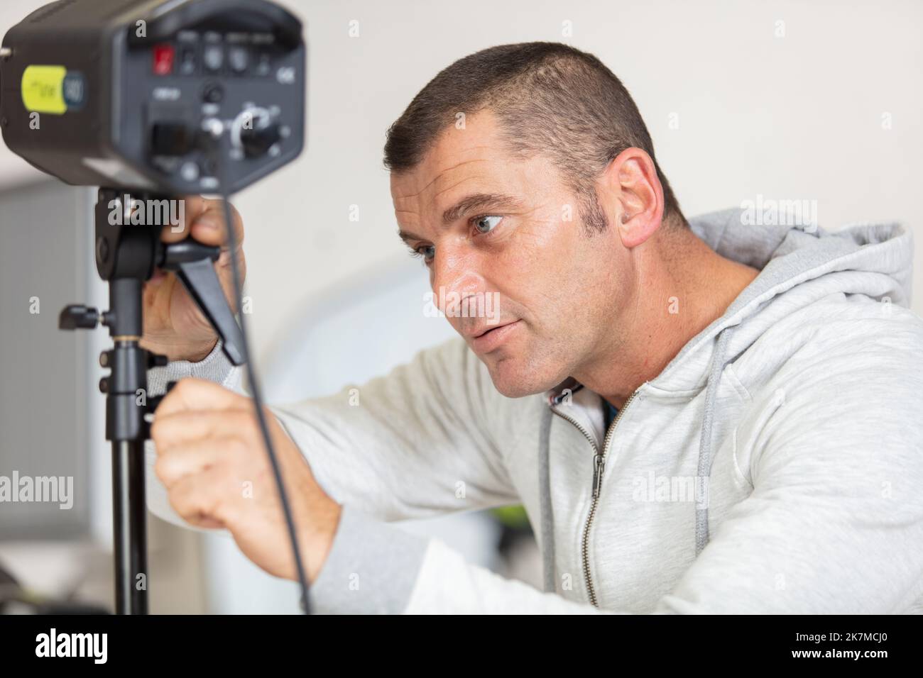 photographe contrôlant la tête d'éclairage stroboscopique du flash studio Banque D'Images