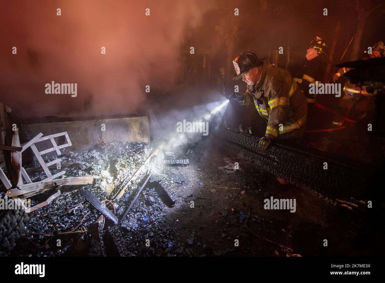 Un commissaire des incendies de la ville de Hampton est commence son enquête sur la cause et l'origine de l'incendie, même si les pompiers travaillent encore autour de lui pour exting Banque D'Images