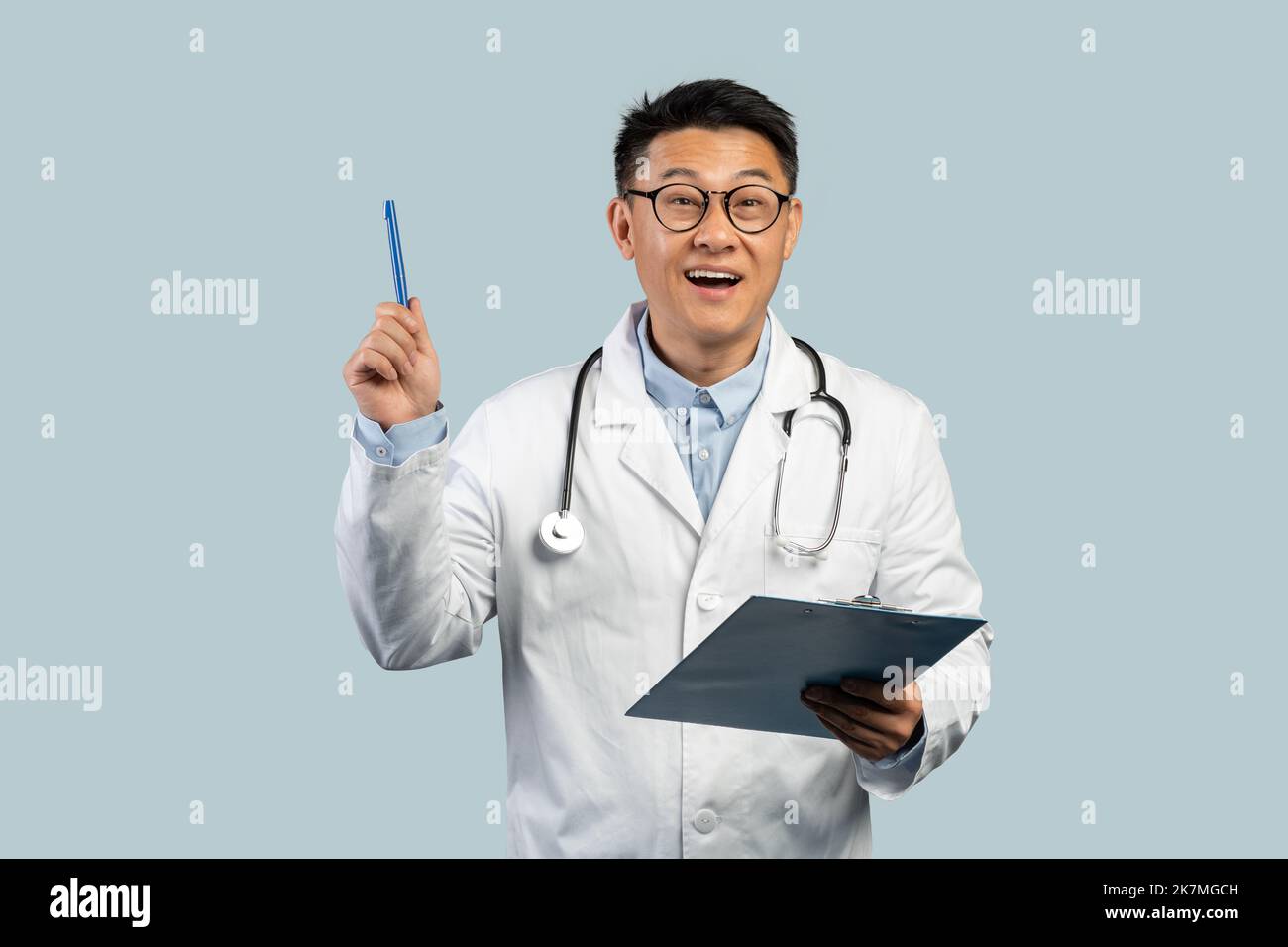 Inspiré médecin chinois d'âge moyen avec un manteau blanc et des lunettes avec un stylo levant de tablette Banque D'Images