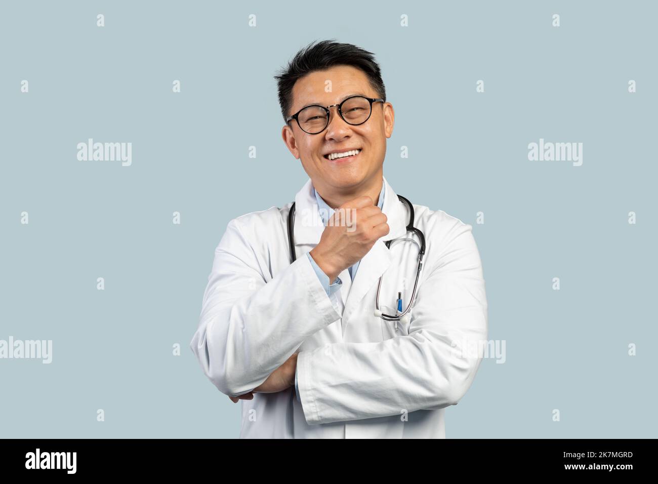 Joyeux pensif chinois d'âge moyen docteur en manteau blanc, lunettes regarder la caméra Banque D'Images