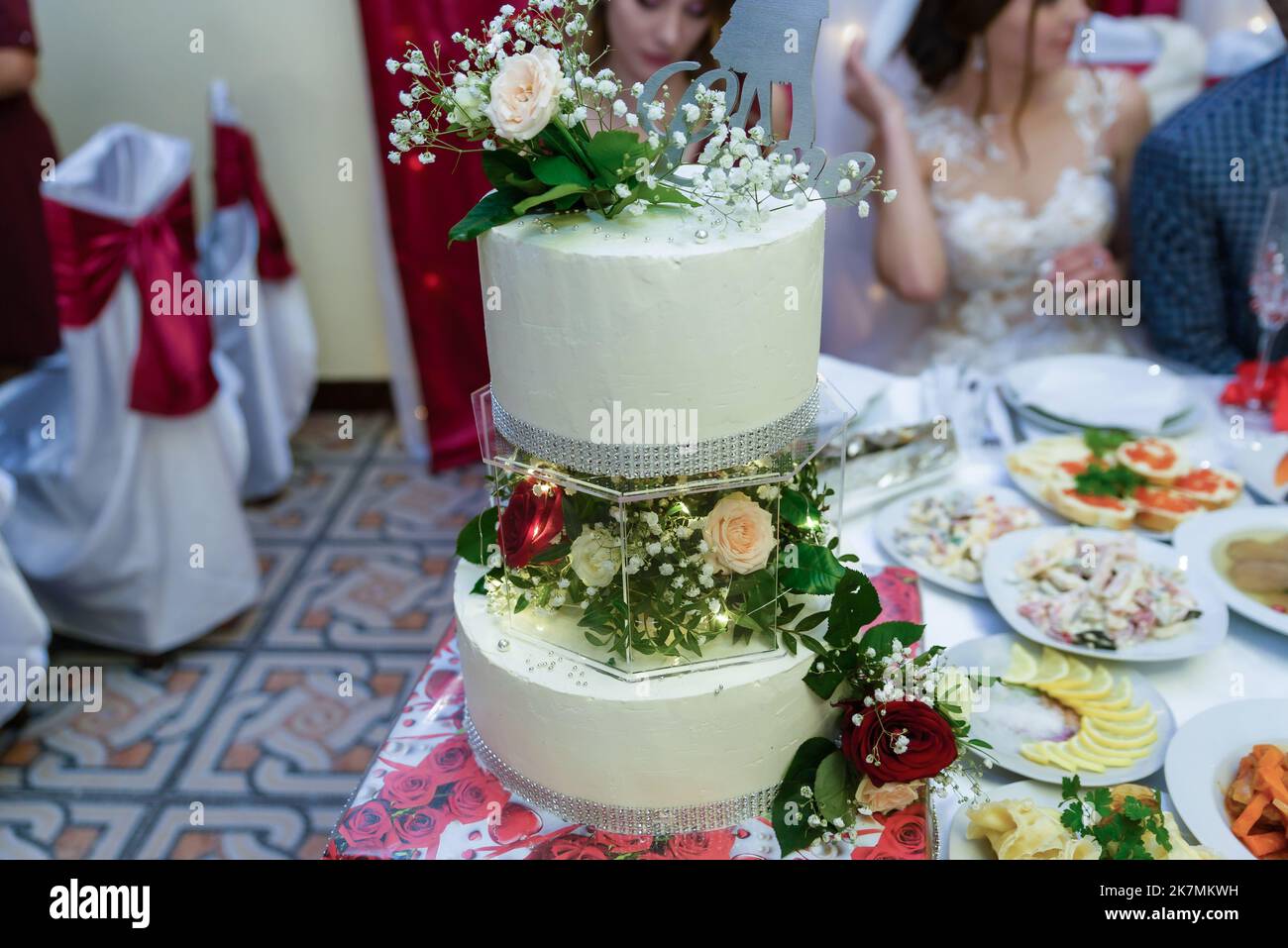 Gâteau de mariage blanc décoré de fleurs sur une table de fête avec beaucoup d'en-cas sur le côté. Fleurs violettes au premier plan. Mariage. Réc Banque D'Images