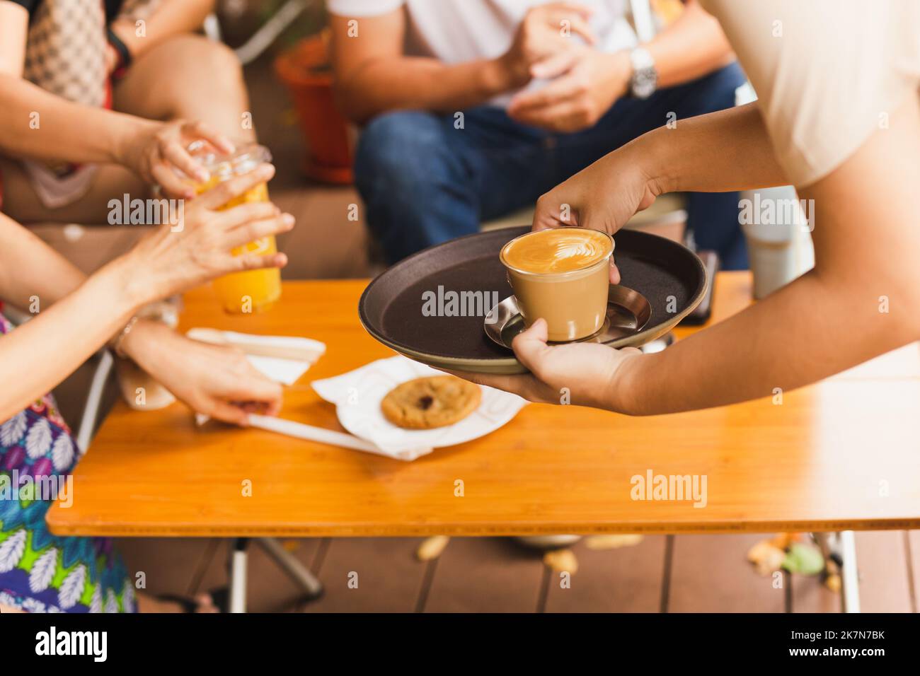 Serveuse servant du café au lait chaud au client au café. Banque D'Images