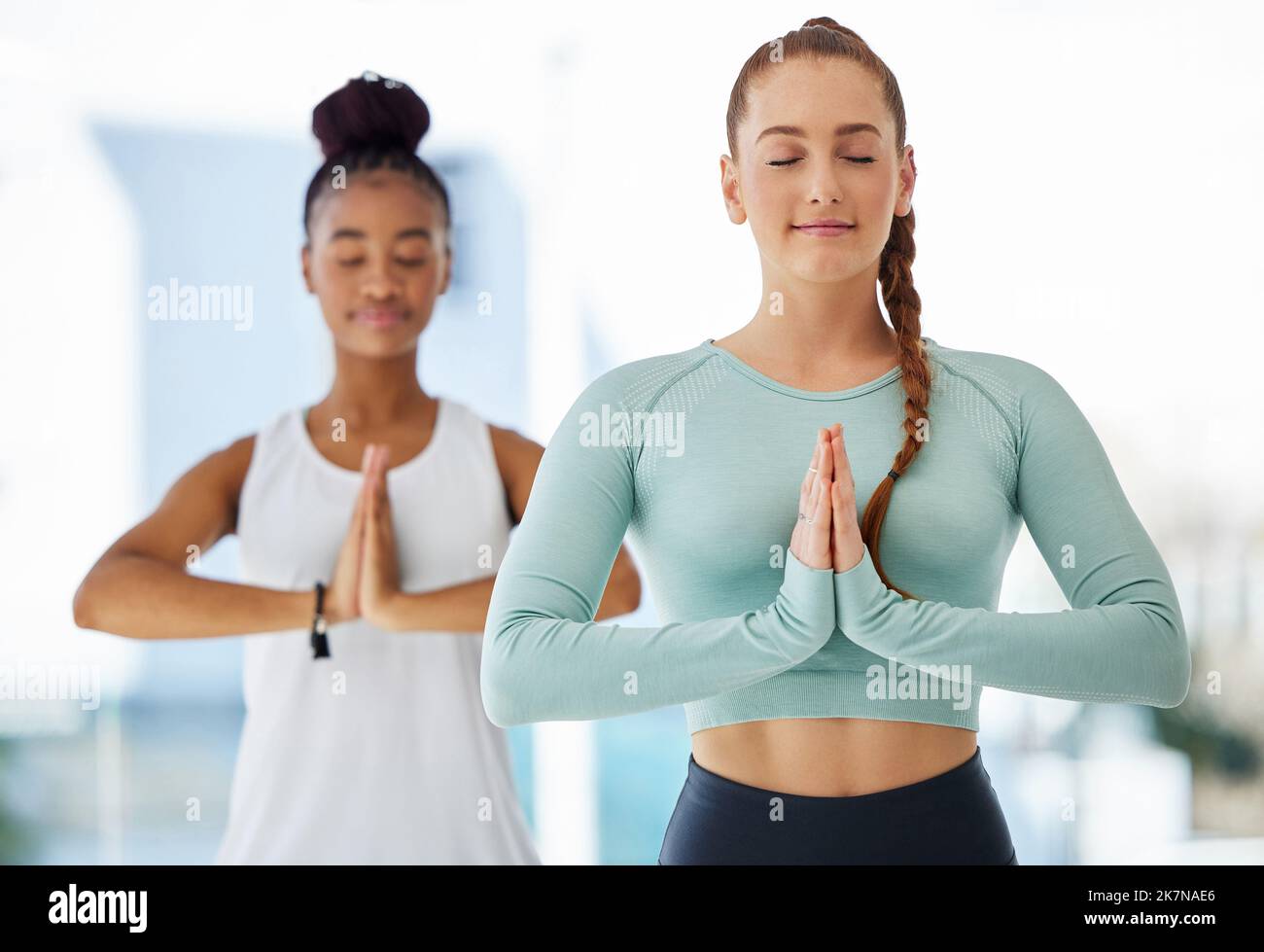 Nous méditons toujours ensemble. deux jeunes femmes se tenant ensemble et pratiquant le yoga en studio. Banque D'Images