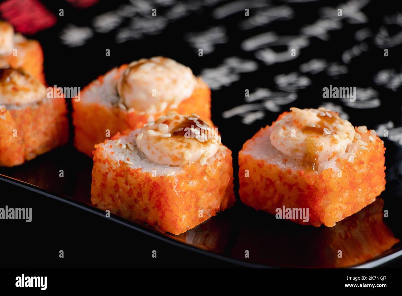 Petits pains à sushi avec caviar sur une assiette noire. Il sert de la cuisine japonaise au restaurant. Rouleaux d'uramaki. Plat asiatique populaire de riz et de fruits de mer. Banque D'Images