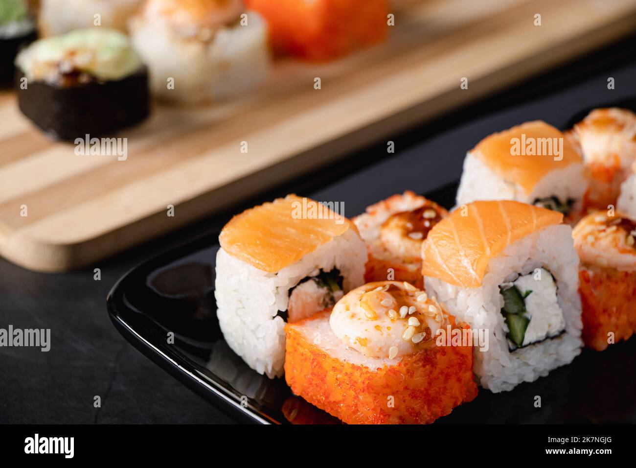 Ensemble de petits pains à sushis de Philadelphie sur une assiette noire. Il sert de la cuisine japonaise au restaurant. Plat asiatique populaire de riz et de saumon. Rouleaux d'uramaki. Banque D'Images