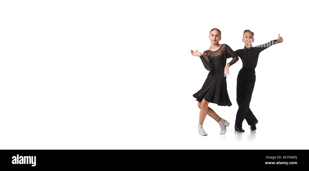 Deux enfants, jeune fille et garçon en costumes de scène noire dansant la danse de salle de bal isolée sur fond blanc. Art, danse sportive, musique, étudier Banque D'Images