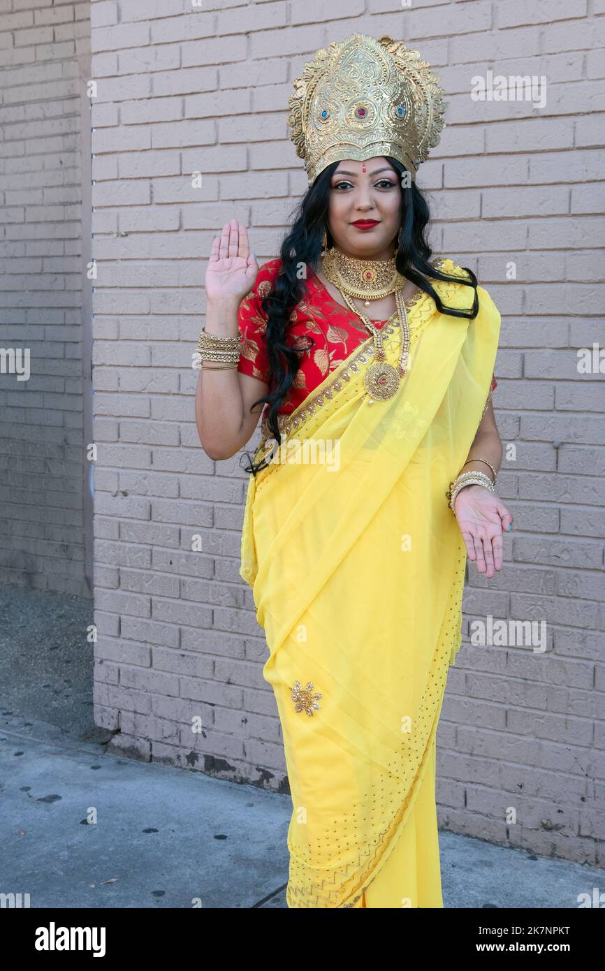 Une jolie femme hindoue portant une couronne et un sari jaune et portant la déesse Lakshmi. Au Diwali 2022 à Queens, New York. Banque D'Images