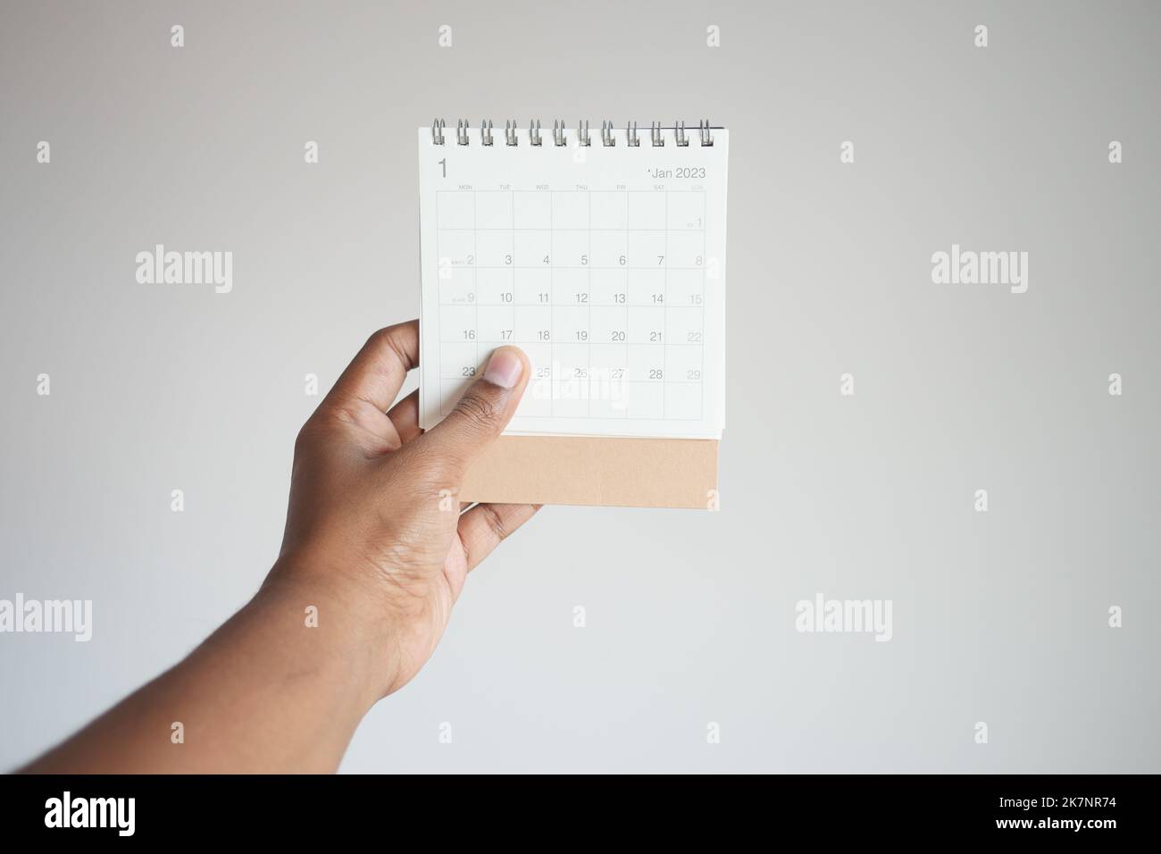 hommes tenant un calendrier de 2023 ans contre le mur blanc Banque D'Images